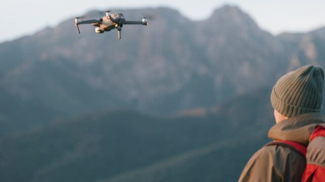 Back view of man backpacker hiker standing on hill top launch drone quadcopter to take video or photo, epic mountain landscape background, hiking in mountains, sunny morning, take off and fly up