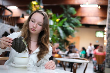 Girl in a cafe dips a Black Croissant into a cup of coffee