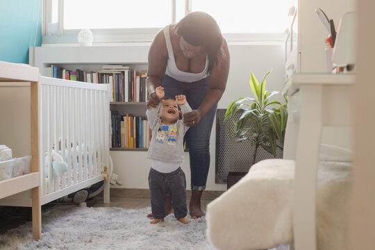 Baby taking first steps with mother's help at home, learning to walk