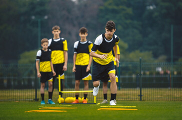 Youth Football Player Running on Training Drill. Teenagers in Soccer Training Sportswear Exercising...