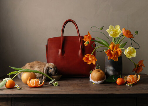 Portrait of brown rabbit with leather bag flowers