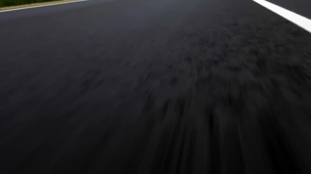 Low-angle, close-up view of white road markings on a freshly paved asphalt highway, emphasizing speed, travel, and road infrastructure.