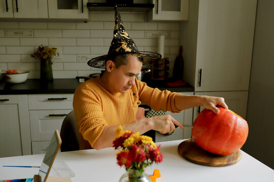 a man cuts a pumpkin for Halloween