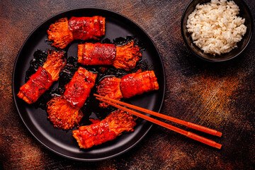 Bacon roll with enoki mushroom grilled with sauce.