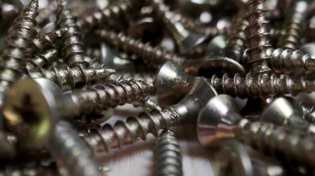 Detailed macro shot of a pile of metallic screws, highlighting the threaded surfaces and shiny metal texture.