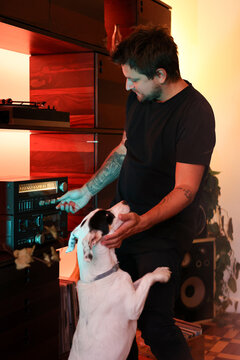 DJ petting his dog and selecting a song to play loud next to speaker