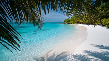 Palm tree leaves create a frame for a view of a white sand beach and turquoise water.