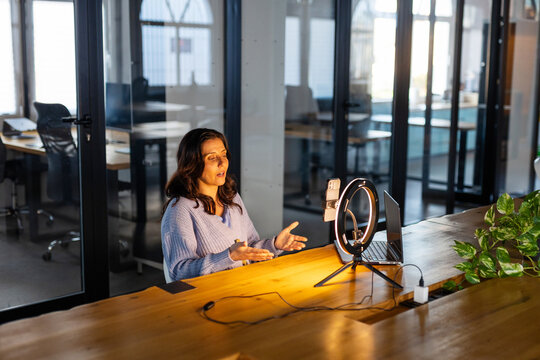 WOMAN USING SMARTPHOME WITH A RING LIGHT IN THE OFFICE