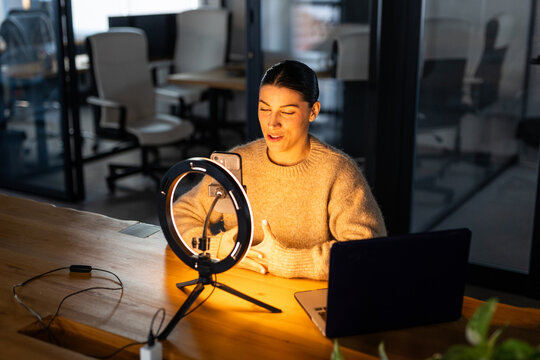 WOMAN USING SMARTPHOME WITH A RING LIGHT IN THE OFFICE