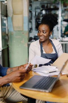 Waitress looking at partial cafe owner checking payments and bills