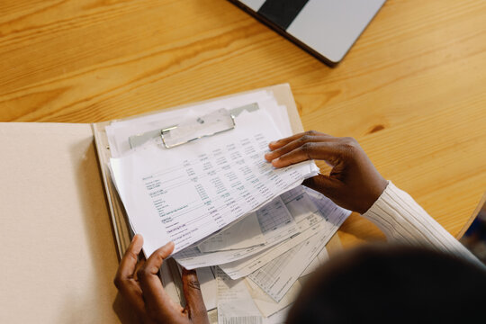 Top of partial black waitress checking financial documents at table