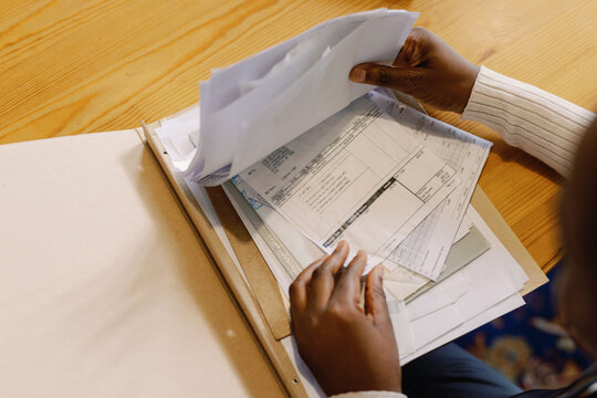 Partial black young waitress checking payments and bills at desk