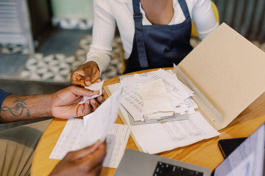 Partial of black waitress and cafe owner checking payments and bills
