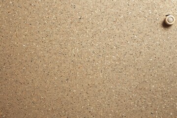 A close-up shot of a beige textured surface with a single round button-like element, showcasing simplicity in design details.