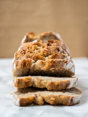 Close-up of a sliced brown loaf of bread. Marble counter with a brown background. Angle view of the slices