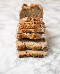 Brown loaf of bread over a marble counter. Angle view of the slices