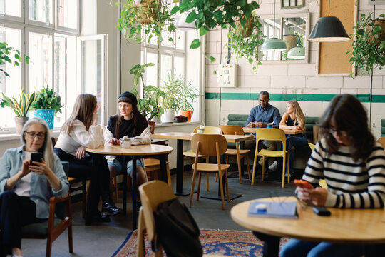 Group of multiethnic people resting and enjoying time together in cafe