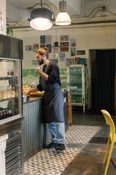 Waiter showing and telling about order to unknown cashier in cafe