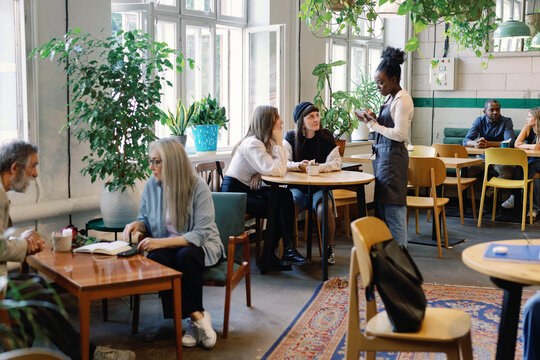 Group of multiracial people resting and spending time together in cafe