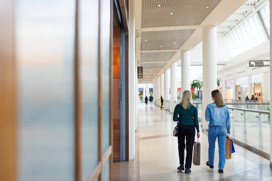 Back view of mother and daughter with shopping bags walking in mall