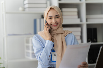 Confident Muslim Professional Navigates Success: A cheerful young businesswoman in a hijab...