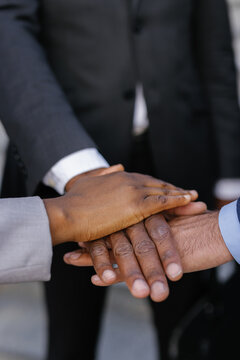 Office worker and coworkers forming hand stack during meeting outdoors