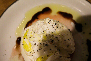 Fresh burrata drizzled with olive oil over ripe cherry tomatoes, seasoned with salt and cracked pepper. 