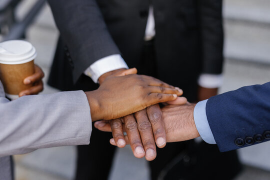 Group of businesspeople stacking hands together during coffee break