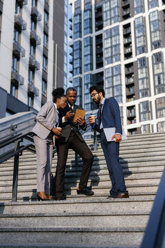 CEO showing something to his office workers on tablet outdoors