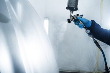 Painting cars in vehicle maintenance service using paint sprayer. Car painter is using HVLP or LVLP...