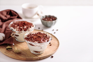 Traditional Italian dessert tiramisu in glasses on white table. Soft focus