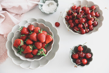 Fresh summer berries into bowls on white table. Summer food concept. Top view