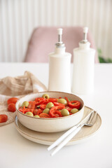 Healthy vegetarian salad with fresh cherry tomato, cucumber, sweet pepper, green olives and lettuce in bowl on white table. Front view