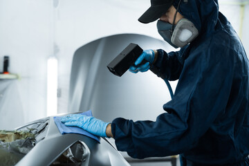 Mechanic is working with anti static gun to prepare metal for paintwork. Using anti static gun to prevent damages and remove dust before covering car with paint.