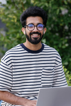 Young Indian man working on laptop in local park