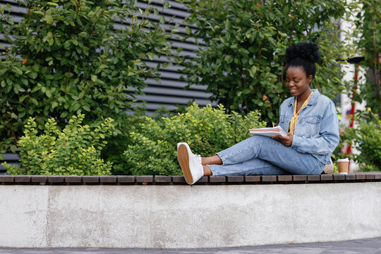 Student doing homework on bench in city park