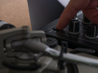 Una mano humana manipulando una mesa de mezclas de deejay.