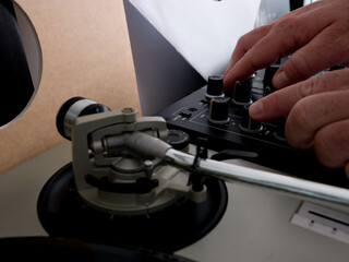 Una mano humana manipulando una mesa de mezclas de deejay.