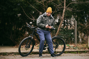 Fototapeta premium Man Texting on Cell Phone While Leaning on a Mountain Bike