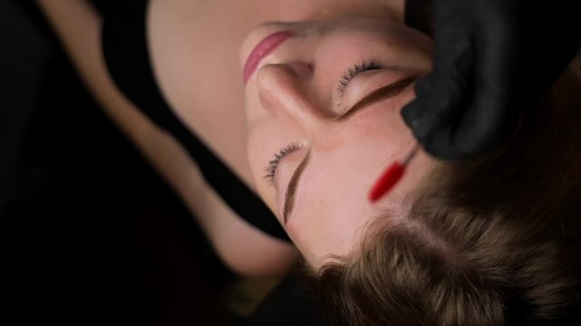 Master with the help of a brush tucks eyebrows after permanent makeup Permanent eyebrow makeup, performing eyebrow tattoo PMU