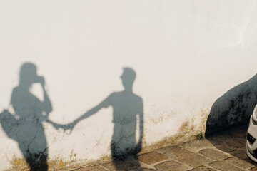 Long shadows of a couple silhouetted against a white wall