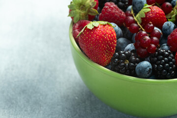Mix of ripe colorful berries in bowl photography . Blueberry , strawberry , raspberry , blackberry and red currant . Top view