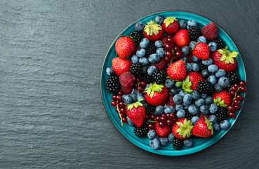 Mix of ripe colorful berries in bowl photography . Blueberry , strawberry , raspberry , blackberry and red currant . Top view