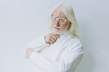 Portrait of a stylish elderly man with long white hair and glasses, wearing a white turtleneck sweater against a soft white background, conveying elegance and sophistication