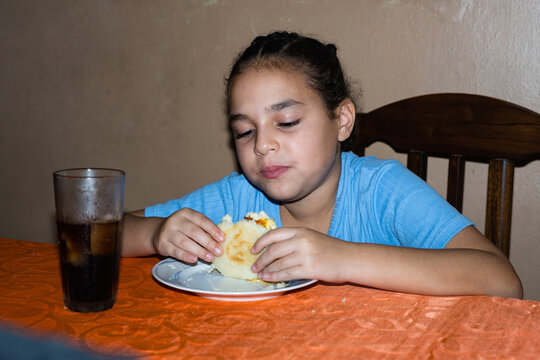 A girl eating an arepa at home