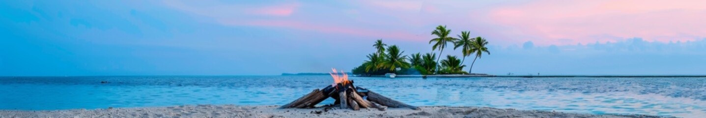 Naklejka premium Sunset Beach Bonfire With Tropical Island, Logs, and Palms, Emphasizing Warmth and Relaxation