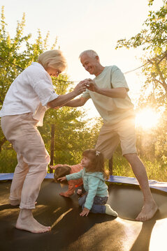 Grandparents with two grandchildren jumping on a trampoline