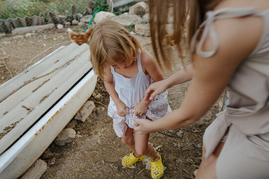 
woman with little daughter collecting eggs in a chicken coop