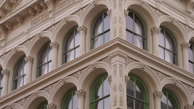 Ornate, arched windows of a historic SoHo building, emphasizing the detailed architectural flourishes and classic design elements.