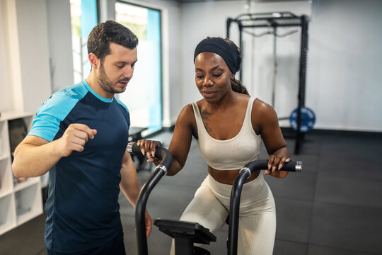 black woman doing sports in the gym with her personal trainer